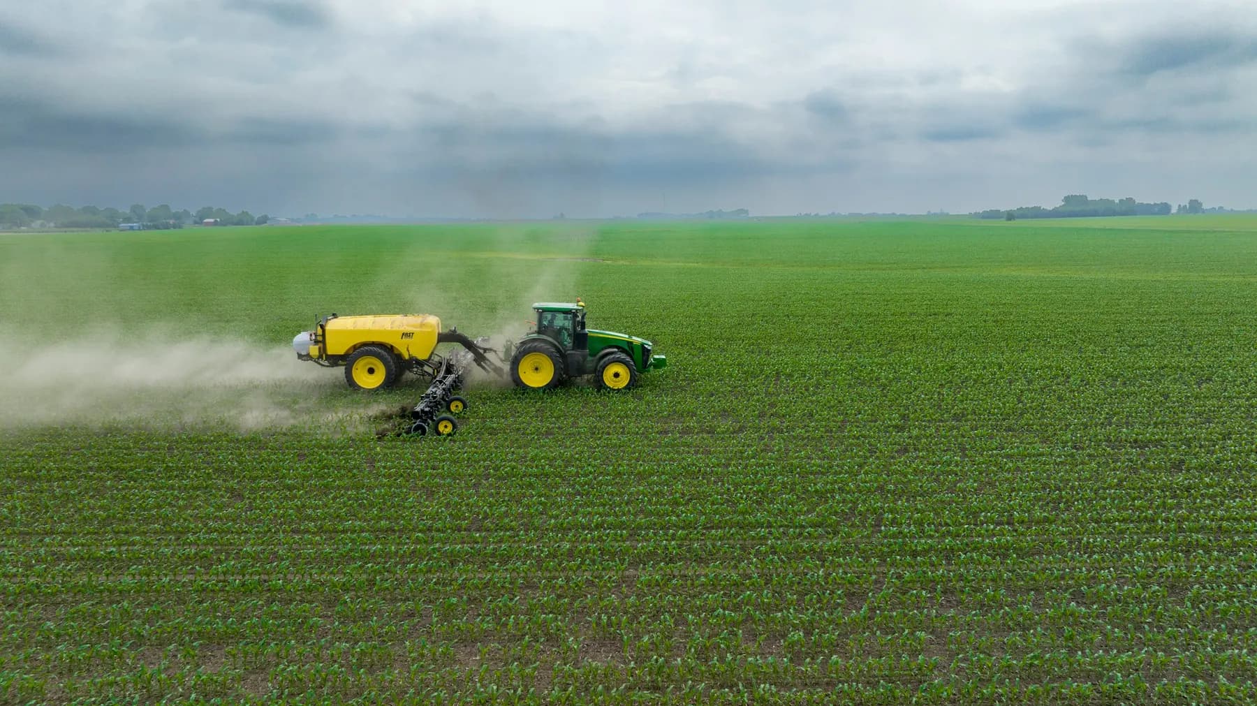 Aerial view of a tractor sprayer working across a green field